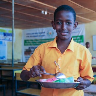 Abdullahi Ali enjoys a school meal at Abdullahi Isse primary and secondary school in Galkayo, Somalia. Photo credit: WFP/Patrick Mwangi